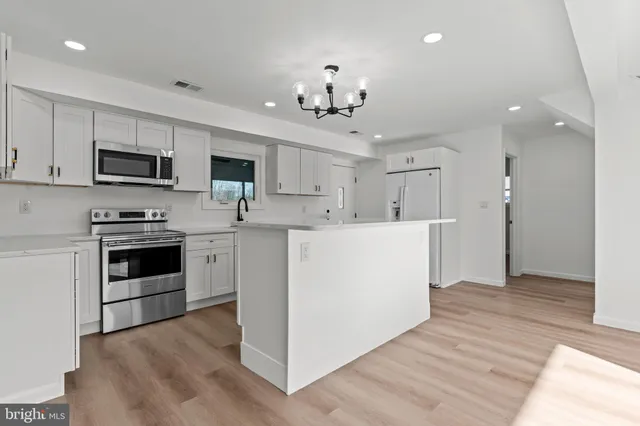 a kitchen with kitchen island granite countertop a stove top oven a sink dishwasher and a refrigerator with wooden floor