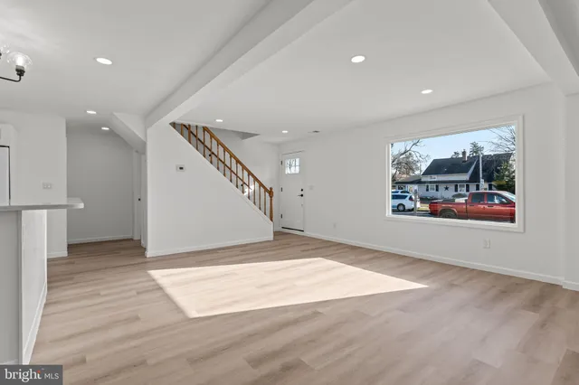 an empty room with wooden floor and hallway