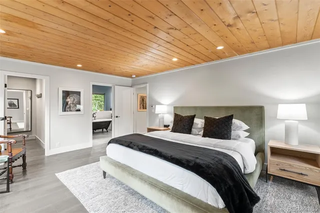 a spacious bedroom with a bed a table and potted plant