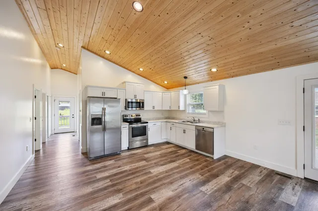 a kitchen with stainless steel appliances kitchen island granite countertop a stove cabinets and wooden floor