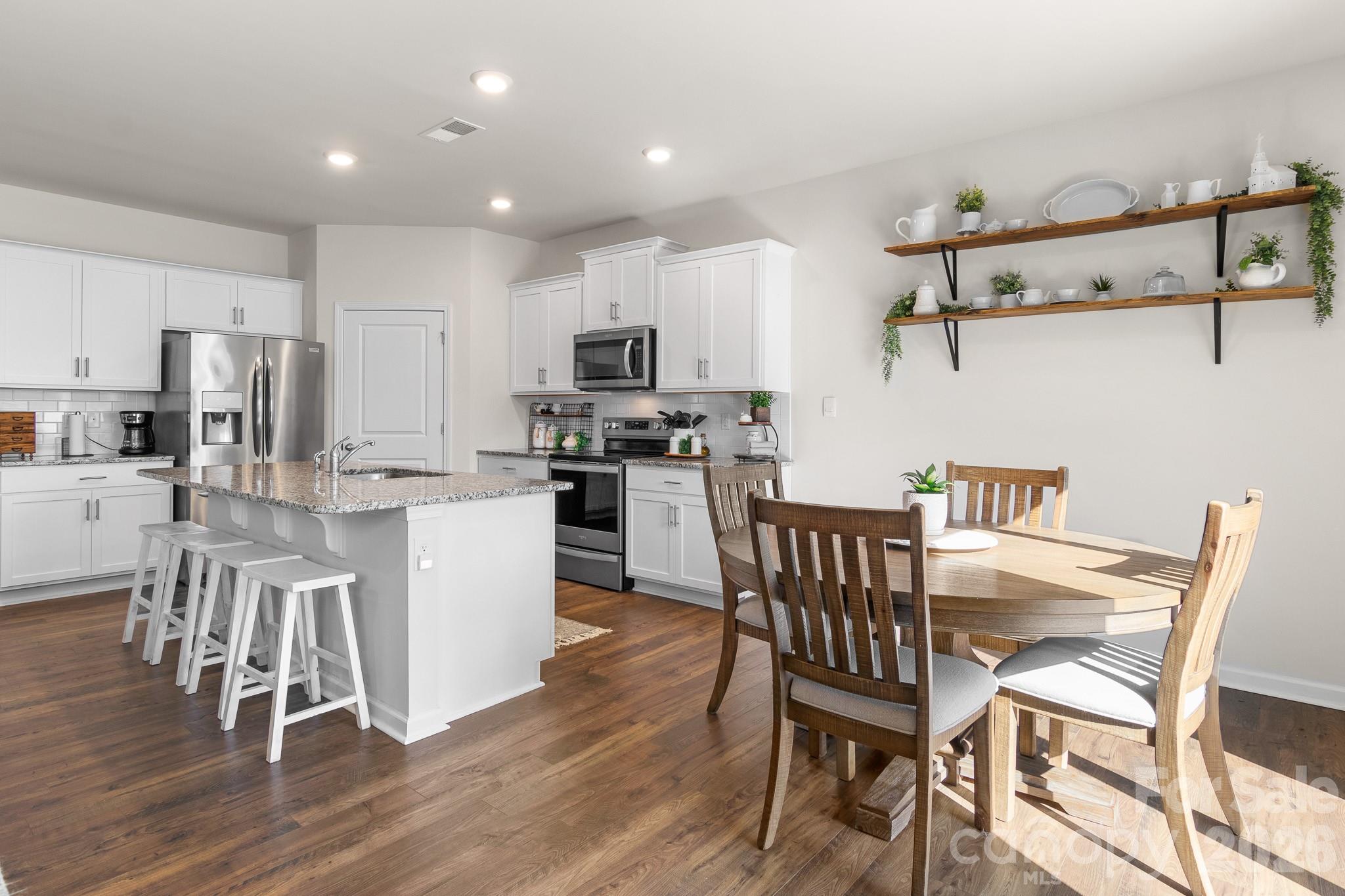 744 Saddlebred Lane Locust, NC 28097 - Photo 12 of 47 a kitchen with stainless steel appliances granite countertop a dining table chairs refrigerator and microwave