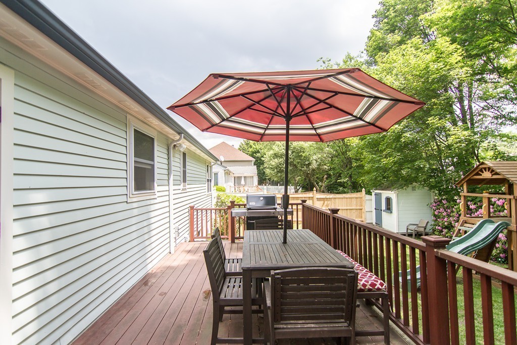 88 Selwyn Road Newton, MA 02461 - Photo 16 of 26 a view of a patio with table and chairs under an umbrella with wooden floor and fence