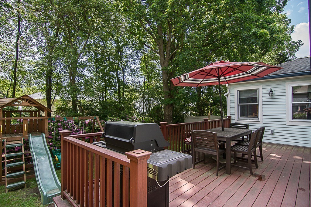88 Selwyn Road Newton, MA 02461 - Photo 17 of 26 a view of a roof deck with table and chairs under an umbrella with wooden floor and fence