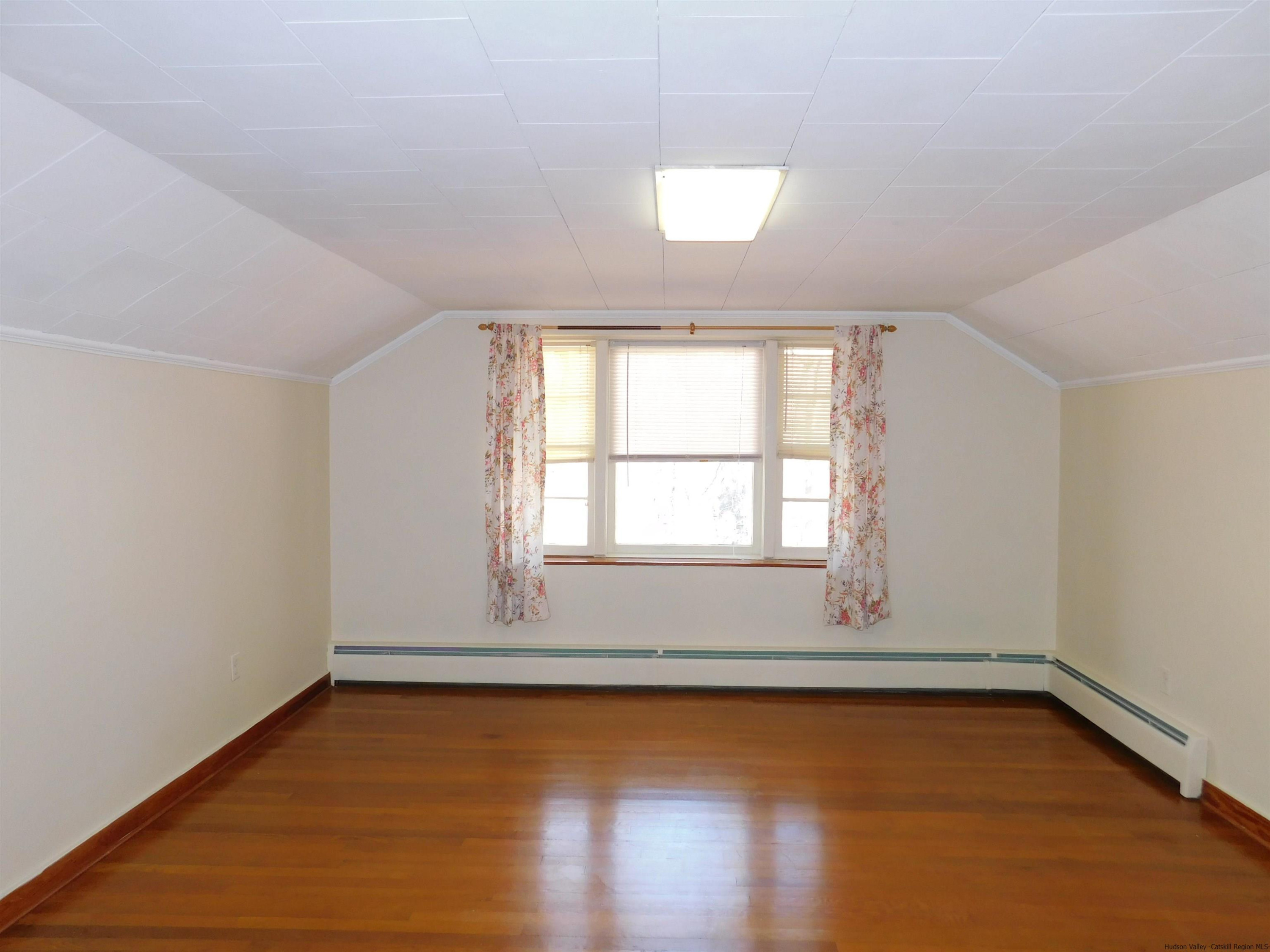 145 Sportsman Road Napanoch, NY 12458 - Photo 17 of 31 an empty room with wooden floor and windows with curtains