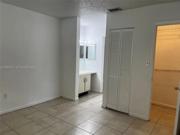a view of a kitchen with white cabinets and a refrigerator