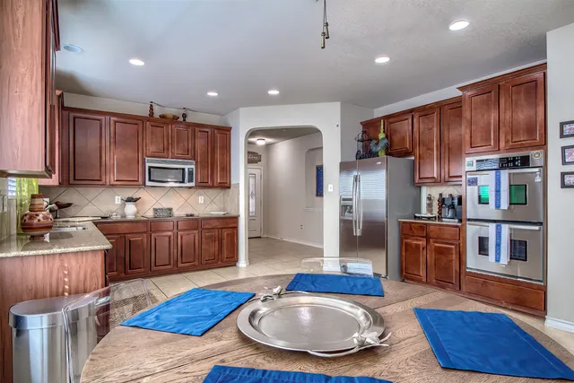 a kitchen with stainless steel appliances granite countertop a refrigerator a stove top oven a sink and cabinets