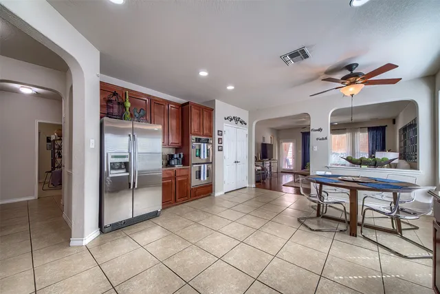 a living room with stainless steel appliances lots of wooden furniture a dining table chair and front door