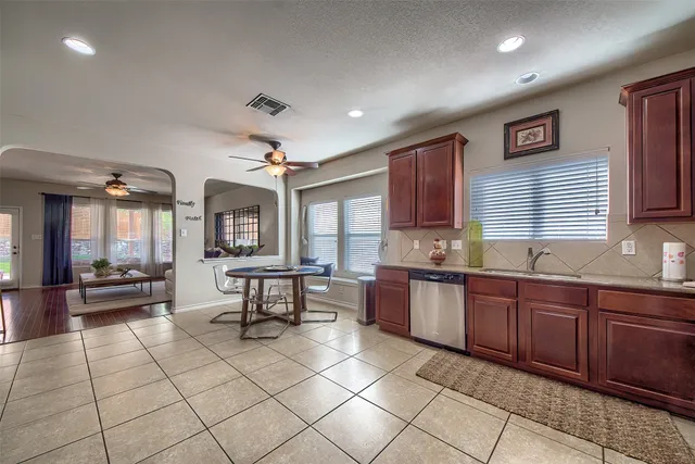 a large kitchen with granite countertop a stove a sink dishwasher and a refrigerator with wooden cabinets