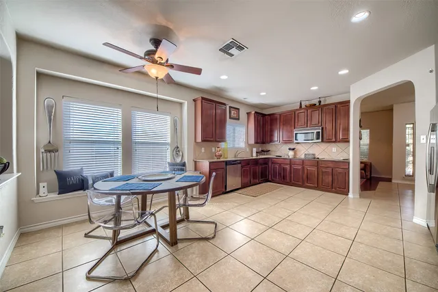 a kitchen with stainless steel appliances granite countertop a sink dishwasher a refrigerator and a dining table with the kitchen view