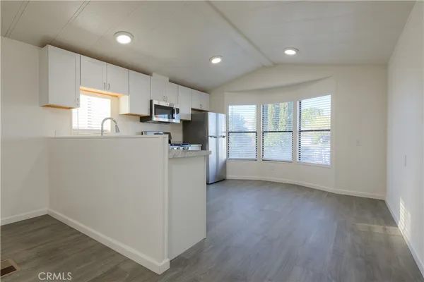 a kitchen with a refrigerator a stove a microwave and a window