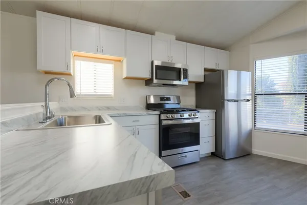 a kitchen with stainless steel appliances a sink a stove a refrigerator cabinets and a window