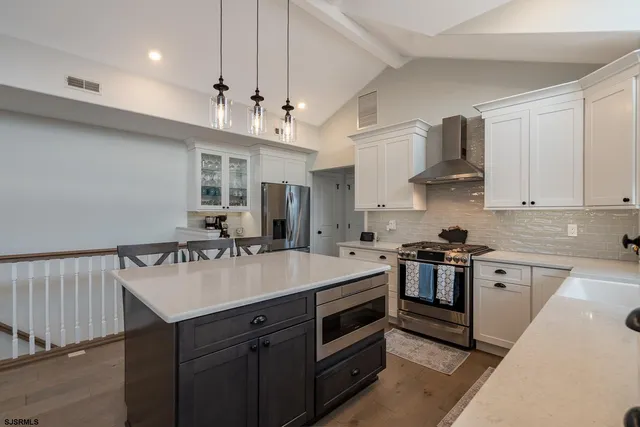 a kitchen with stainless steel appliances a kitchen island a stove a table and chairs in it