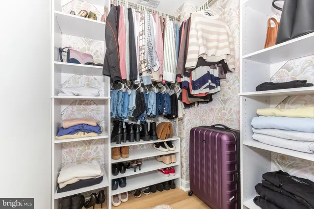 a view of walk in closet with clothes and shoes
