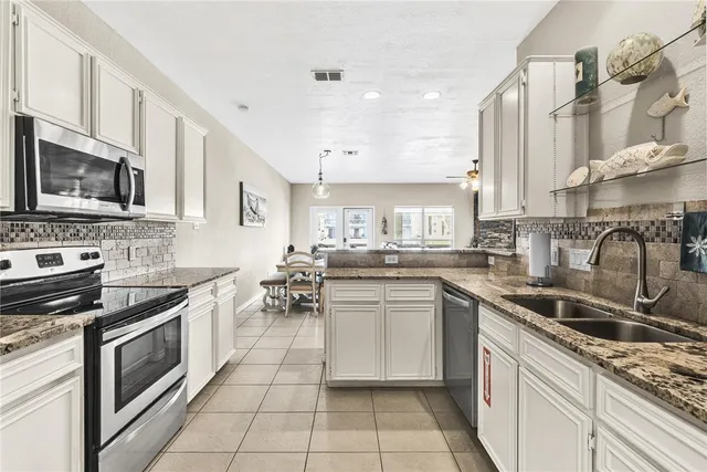 a kitchen with stainless steel appliances granite countertop a sink stove oven and white cabinets