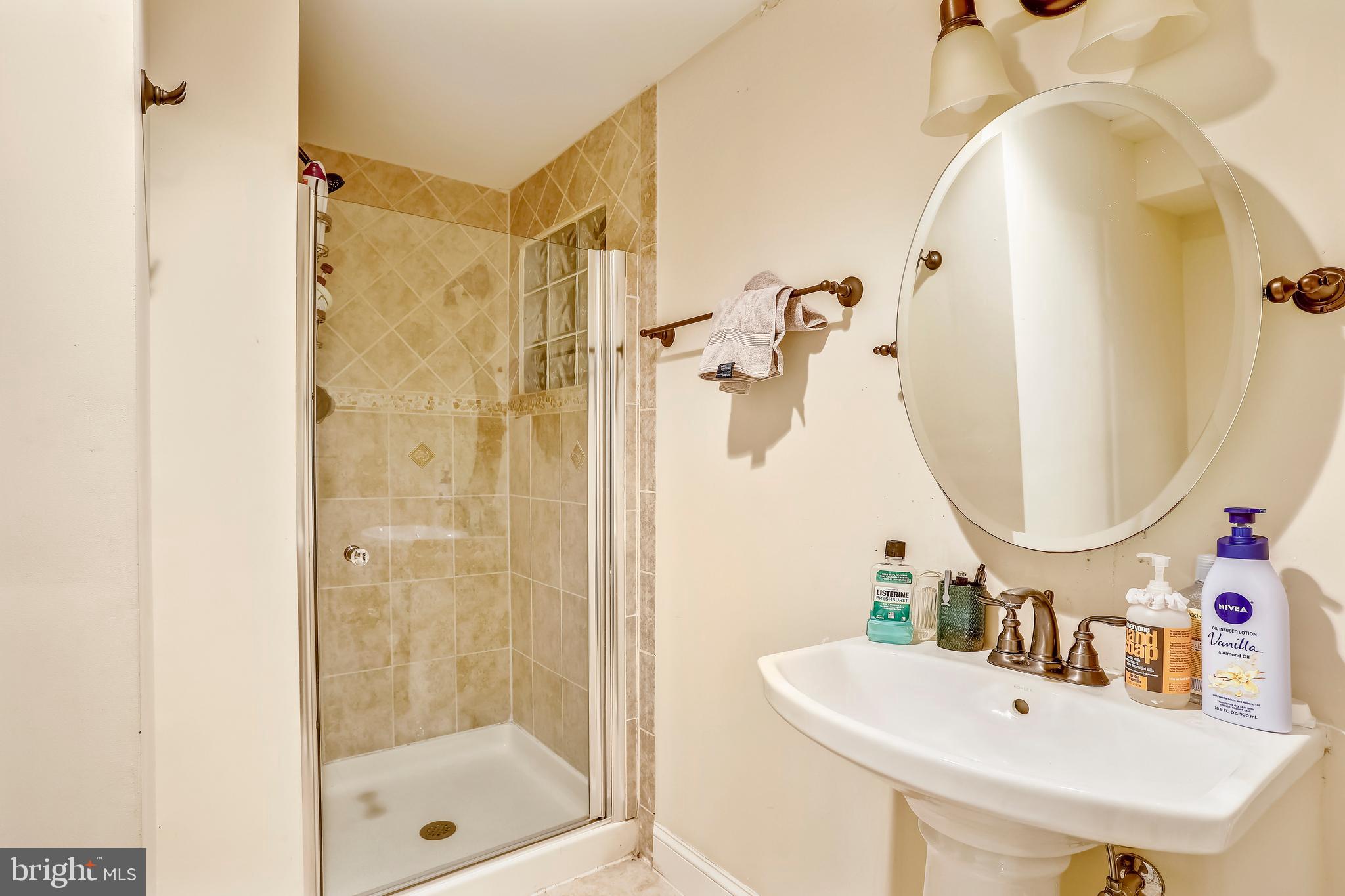 10145 Colebrook Avenue Potomac, MD 20854 - Photo 23 of 30 a bathroom with a sink a glass door shower and a mirror