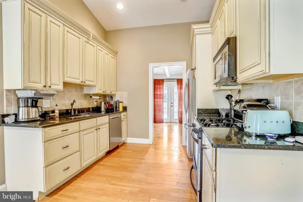 a kitchen with stainless steel appliances granite countertop a stove a sink and a white cabinets