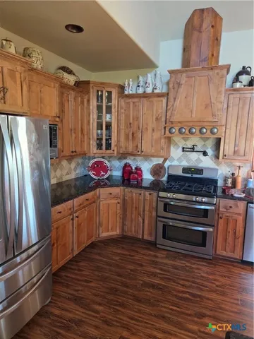 a kitchen with granite countertop a refrigerator and a stove top oven