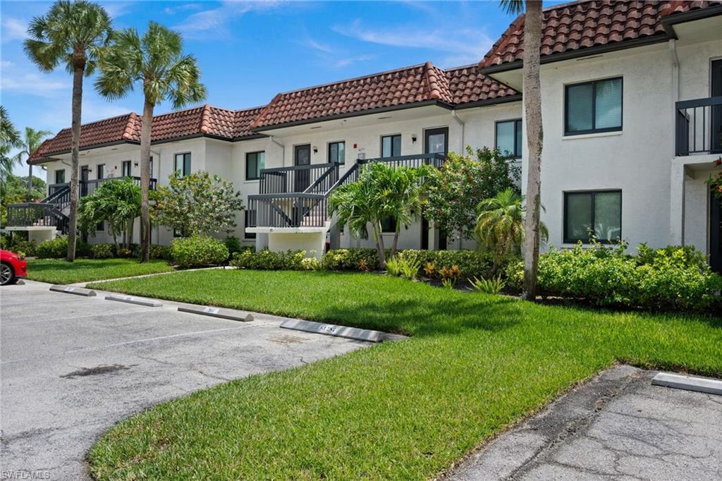 4251 27th Court Southwest, Unit 104 Naples, FL 34116 - Photo 2 of 22 a front view of a house with a yard