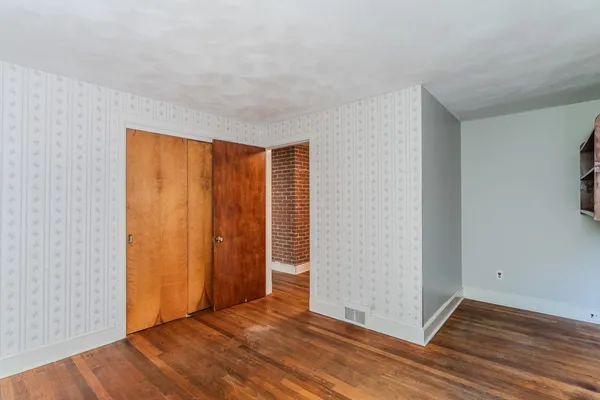 an empty room with wooden floor and closet area