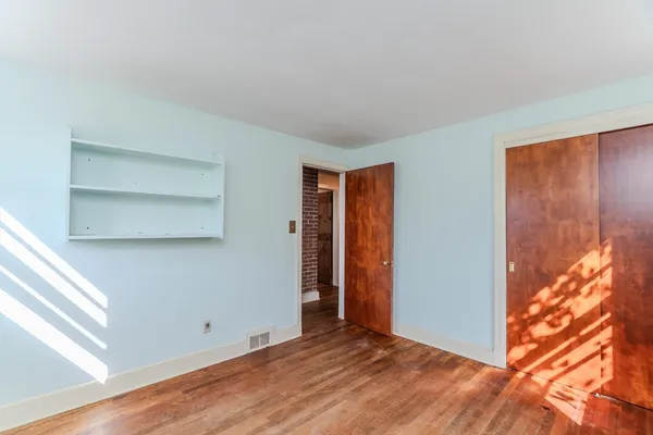 a view of an empty room with closet and a window