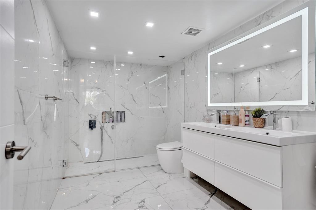 2801 Northeast 183rd Street, Unit 101W Aventura, FL 33160 - Photo 13 of 39 a bathroom with a double vanity sink a toilet a mirror and shower