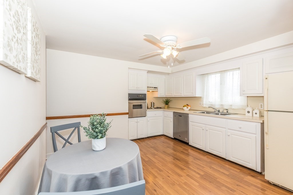 373 Andover Road Billerica, MA 01821 - Photo 7 of 23 a kitchen with a refrigerator a sink dishwasher and white cabinets with wooden floor