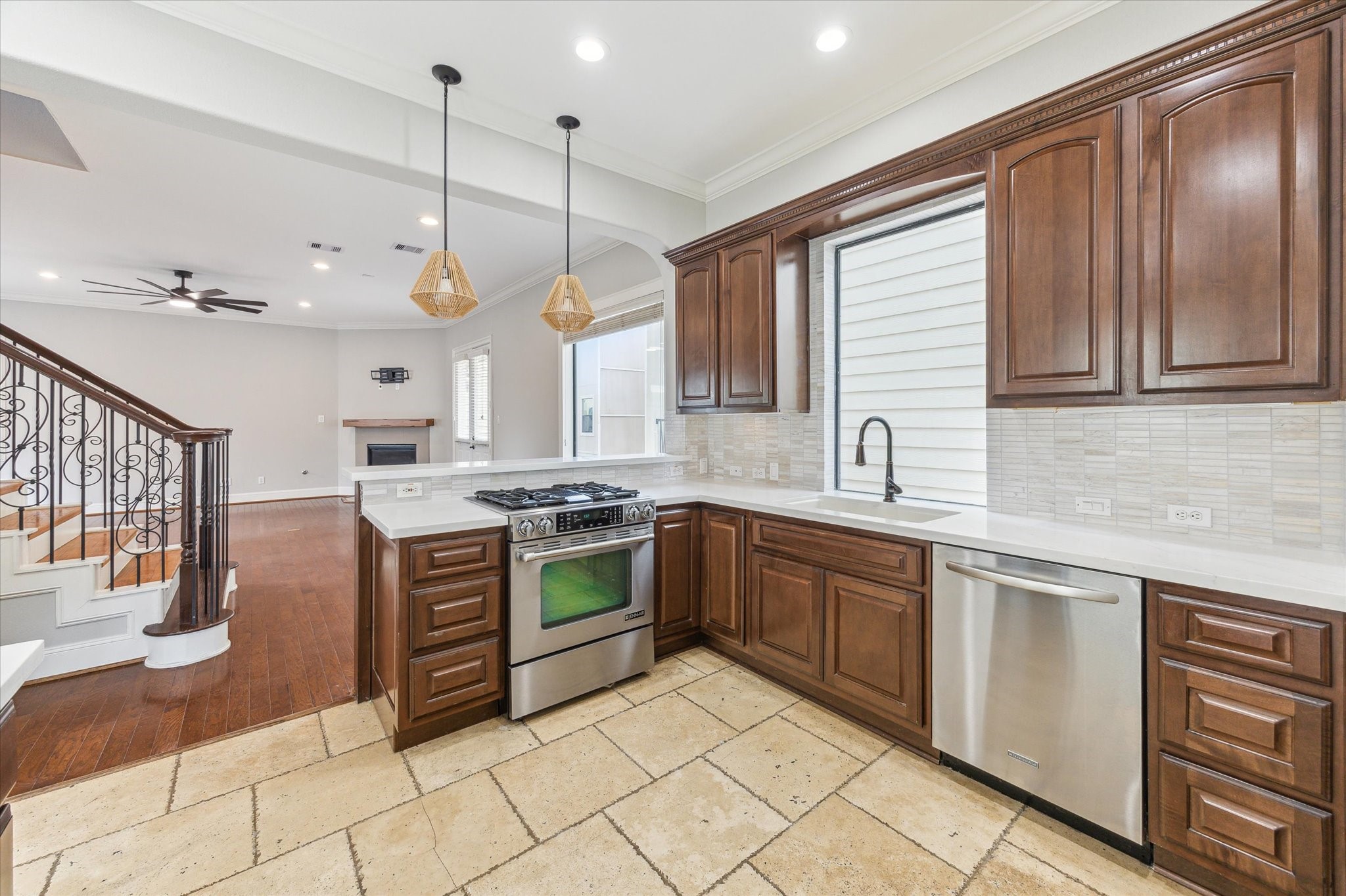 1512 Thompson Street, Unit 3 Houston, TX 77007 - Photo 7 of 32 This home offers a spacious open-concept kitchen and living area. The kitchen features elegant wooden cabinetry, stainless steel appliances, and recently added quartz countertops (2025). The living area includes hardwood floors, a ceiling fan, and an elegant staircase, creating a warm and inviting space.