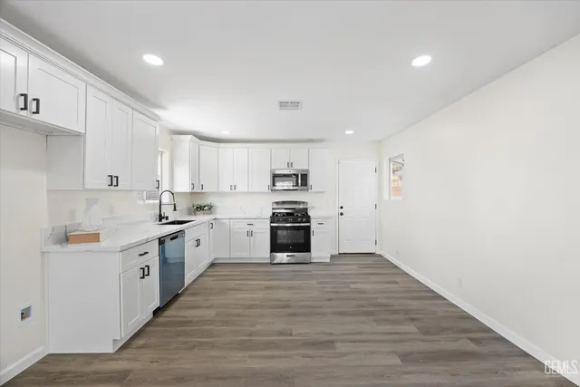 a large kitchen with white cabinets and wooden floor