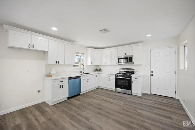 a large kitchen with cabinets wooden floor and stainless steel appliances