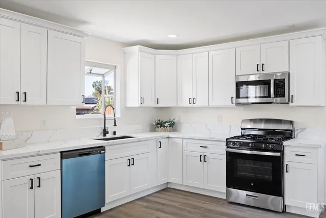 a kitchen with cabinets stainless steel appliances a sink and wooden floor