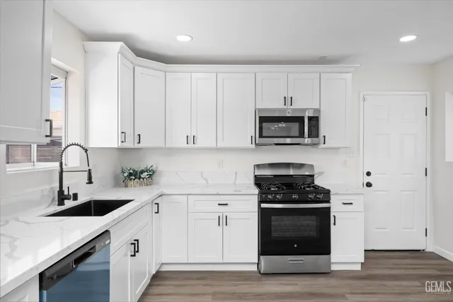 a kitchen with white cabinets and black appliances