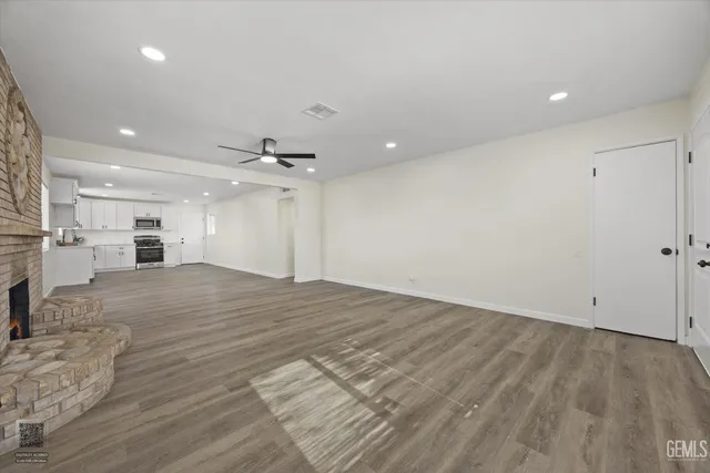 an empty room with wooden floor a kitchen view