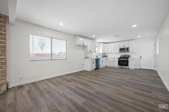 a view of an empty room with a kitchen stove wooden floor and window