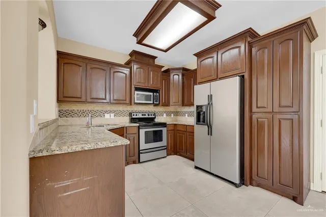 a kitchen with granite countertop stainless steel appliances a refrigerator sink microwave and cabinets