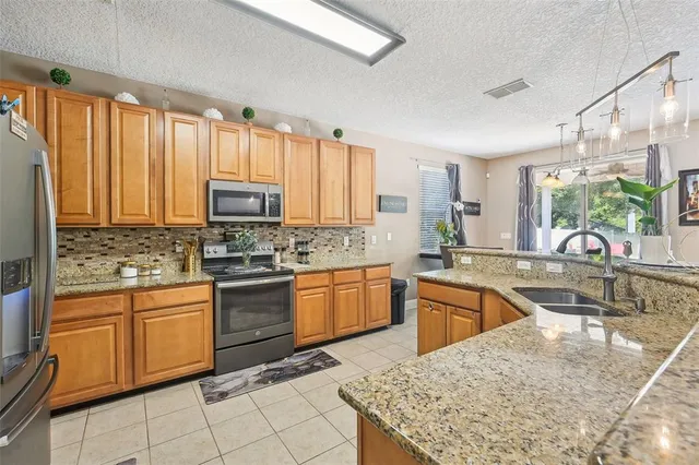 a kitchen with stainless steel appliances granite countertop a stove top oven a sink dishwasher and white cabinets with wooden floor