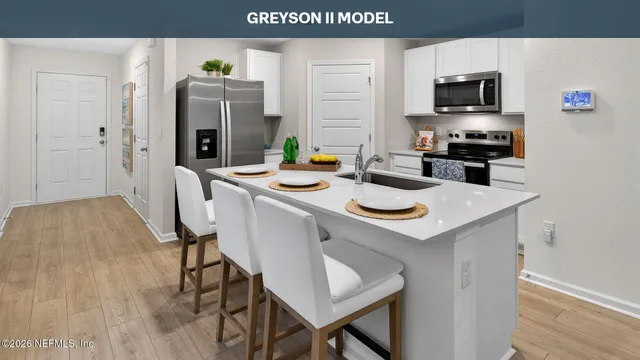 a kitchen with a sink a microwave a refrigerator and chairs