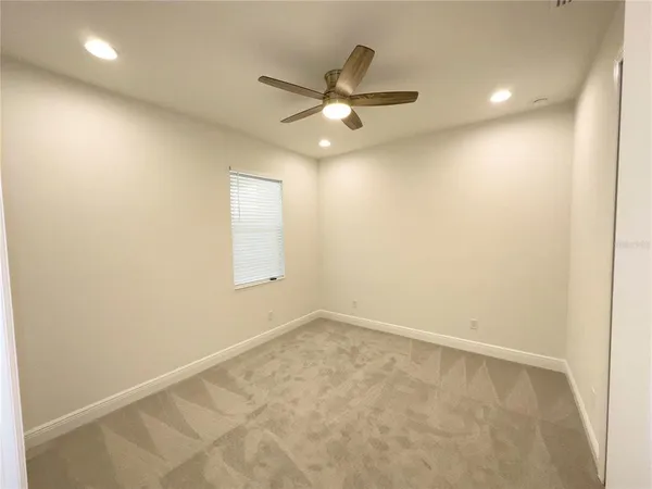 an empty room with a ceiling fan and window