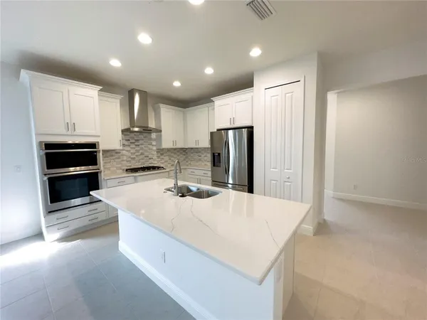 a large kitchen with kitchen island a sink stainless steel appliances and cabinets