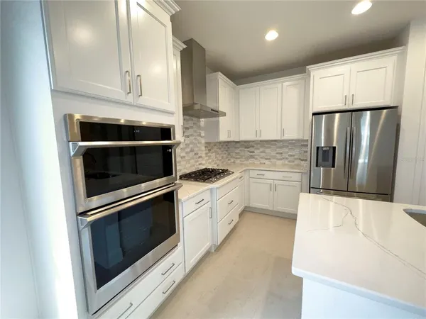 a kitchen with granite countertop white cabinets and stainless steel appliances