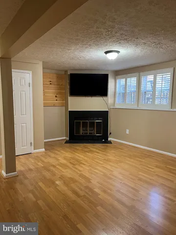 an empty room with wooden floor a fireplace and windows