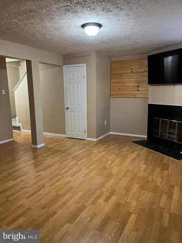 a view of an empty room with fire place and a flat screen tv