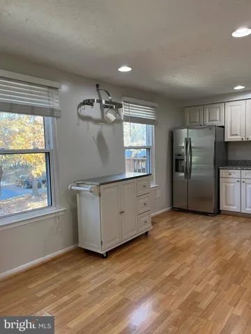 an empty room with wooden floor cabinet and windows