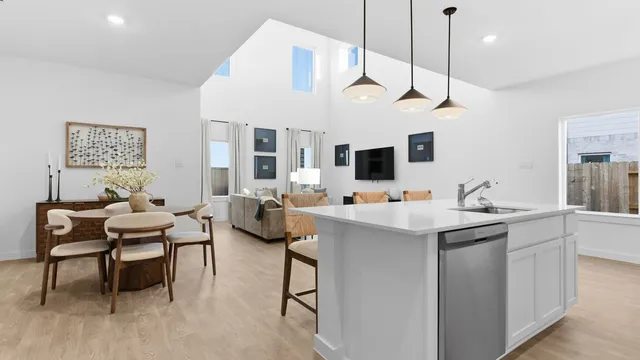 a kitchen with a sink a counter space appliances and a view of living room