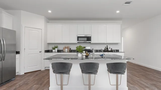 a kitchen with stainless steel appliances granite countertop a table chairs sink and cabinets
