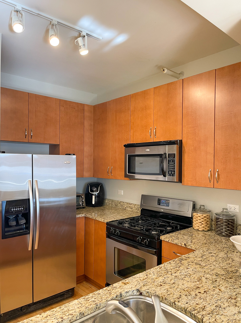 451 West Huron Street, Unit 709 Chicago, IL 60654 - Photo 6 of 19 a kitchen with stainless steel appliances granite countertop a stove a sink and a refrigerator
