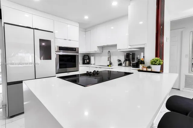 a kitchen with stainless steel appliances a sink a stove a refrigerator a washer and dryer