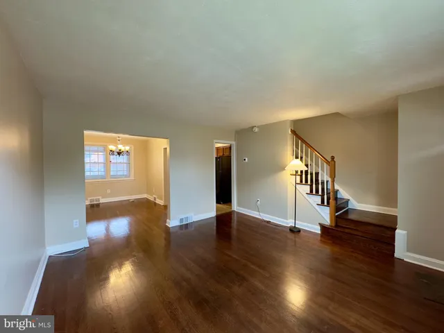 an empty room with wooden floor chandelier and windows