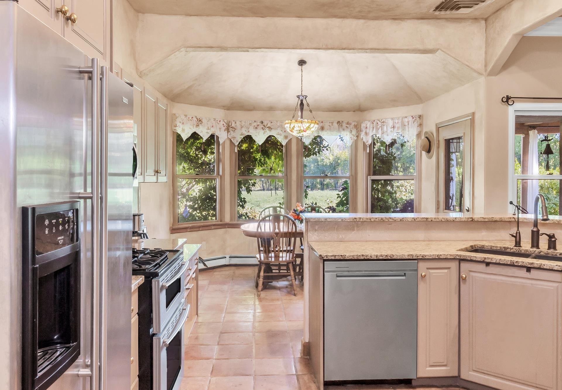 3310 C Road Palisade, CO 81526 - Photo 22 of 41 a kitchen with kitchen island granite countertop a stove a refrigerator and a dining table under a large window