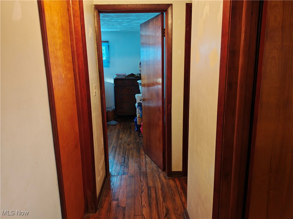 Corridor with dark wood-type flooring and baseboards
