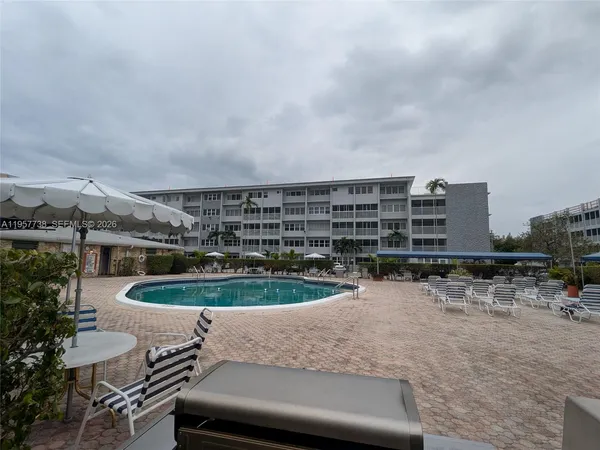 a view of a swimming pool with a chairs and table in the patio